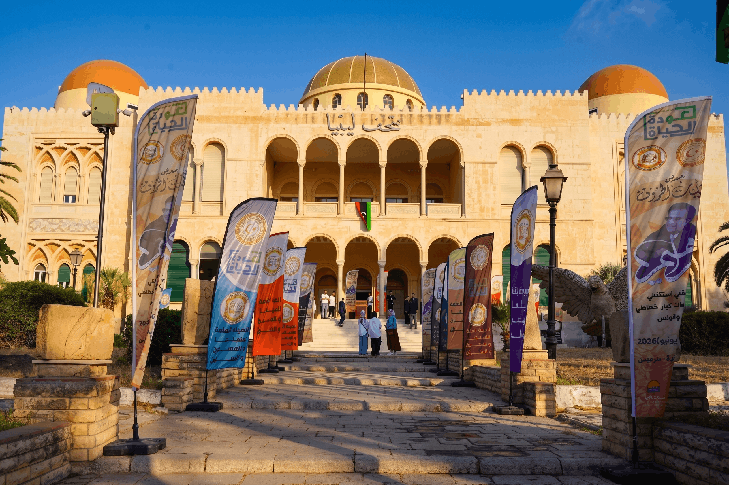 الواجهة الخارجية لمتحف ليبيا بقباب ذهبية وعلم ليبيا ولافتات ترويجية.