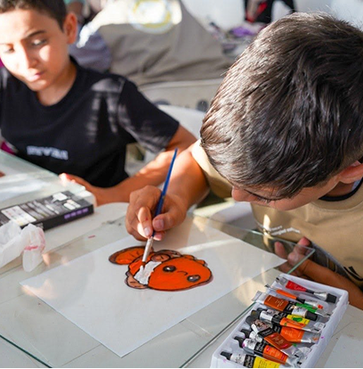 طفل يرسم سمكة مهرج بالألوان المائية.